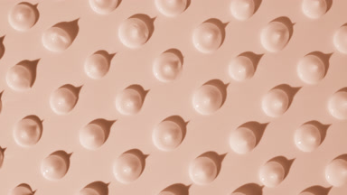 Drops of beige cream appear from the shadow on beige background