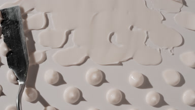 Drops of white day cream are being smeared on white background