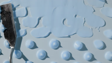 Drops of blue day cream are being smeared on blue background