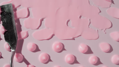 Drops of pink day cream are being smeared on pink background