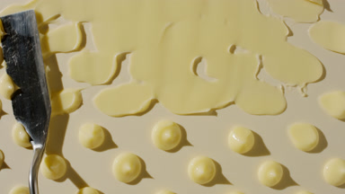 Drops of yellow day cream are being smeared on yellow background