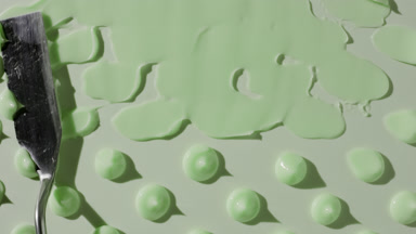 Drops of green day cream are being smeared on green background