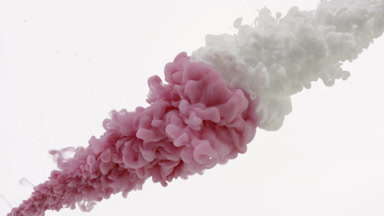 Pink and white inks being injected in water on white background