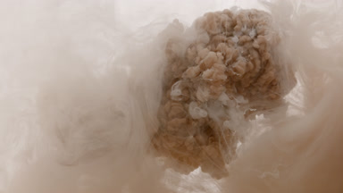 Brown and white inks injected in cloudy water mixing into beige