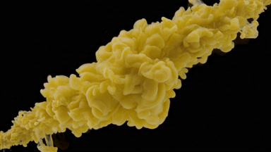 Yellow ink injected in water from corners on black background