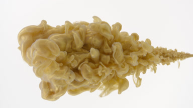 Macro of gold ink is being injected in water on white background