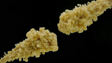 Gold ink is injected in water from corners on black background