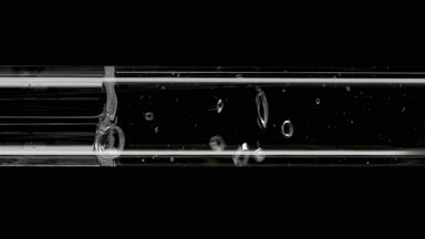 Water is being poured into glass test tube on black background