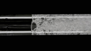 Macro of water is being poured into glass test tube filling it