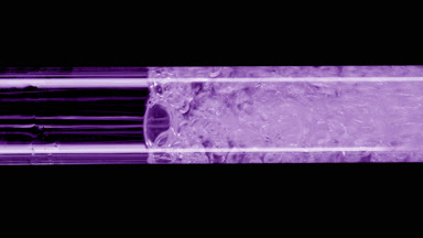 Macro of water is being poured into violet test tube filling it