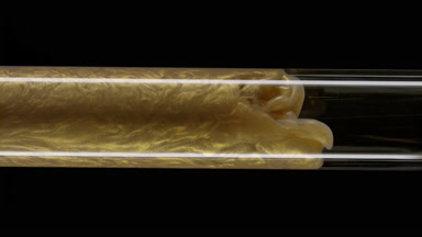 Gold ink flows inside test tube with water on black background