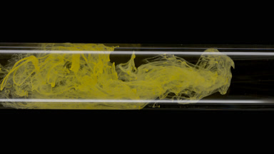 Yellow ink flows inside test tube with water on black background