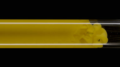Macro of yellow ink flows inside test tube with water filling it