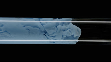 Macro of blue ink flows inside test tube with water filling it