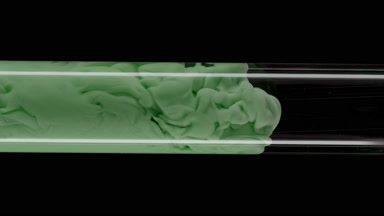 Macro of green ink flows inside test tube with water filling it