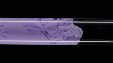 Macro of purple ink flows inside test tube with water filling it