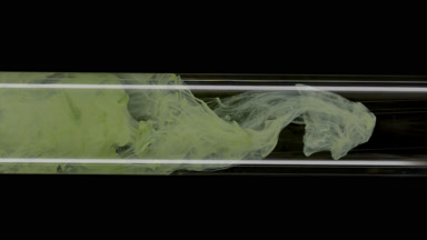 Green ink flows inside test tube with water on black background
