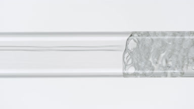 Water is being poured into glass test tube on white background