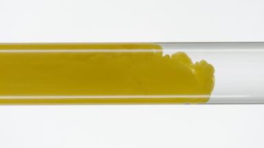 Yellow ink flow filling test tube with water on white background