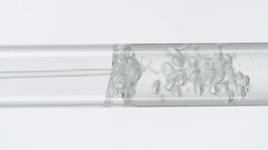 Water poured into glass test tube filling it on white background