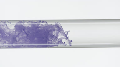 Purple ink filling test tube with water on white background