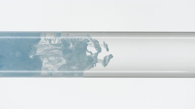 Blue ink filling glass test tube with water on white background