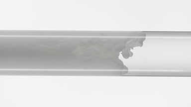 Grey ink flows inside test tube with water on white background