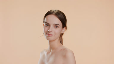 Woman with long brown hair in ponytail turns to camera smiling