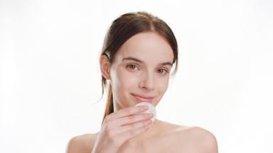 Gorgeous slim woman strokes chin using cotton pad smiling widely