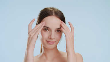 Beautiful woman strokes forehead smiling wide on blue background