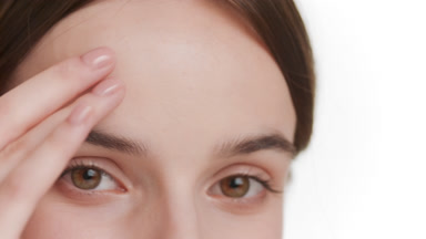 Beautiful young woman strokes her forehead on white background