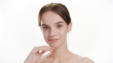 Woman strokes jawline turning head to camera and smiles widely