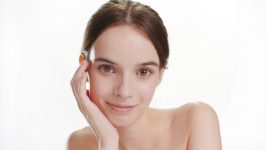 Beautiful Caucasian woman puts head on hand smiling for camera