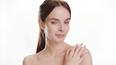 Gorgeous woman strokes shoulder turning head and smiles widely