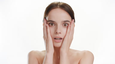 Pretty young Caucasian woman puts hands on cheeks being scared