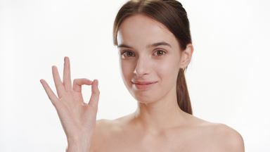 Good-looking young slim Caucasian woman shows OK sign smiling