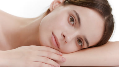 Pretty Caucasian woman puts head on bent arm on white background