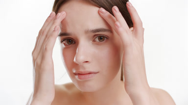 Woman touches her forehead and finds skin problems disappointing