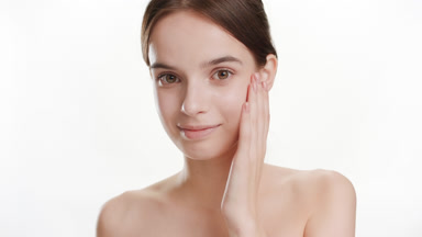 Beautiful woman touches cheeks stroking them and smiles widely