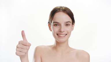 Cute young Caucasian woman shows thumb up gesture smiling widely