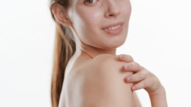 Gorgeous Caucasian woman strokes shoulder turning body to camera