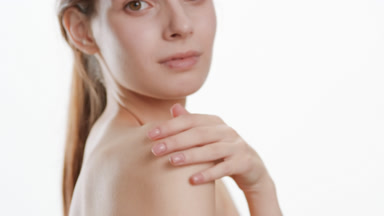Good-looking slim woman strokes shoulder turning body to camera