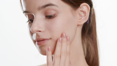 Attractive woman strokes face turning head to camera and smiles