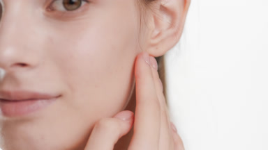 Extreme close-up shot of Caucasian woman strokes jawline smiling