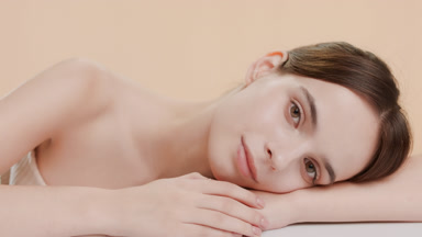 Attractive woman puts head on bent arm lying on white surface
