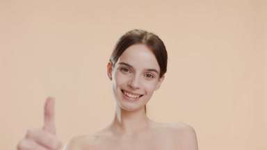 Happy pretty young woman shows thumb up gesture smiling widely