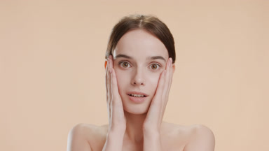 Gorgeous slim Caucasian woman puts hands on cheeks being shocked