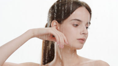 Beautiful woman strokes jawline turning head behind foggy glass