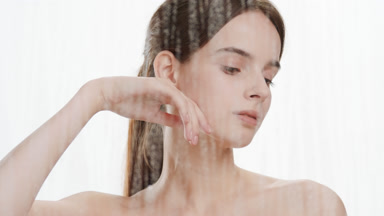 Caucasian woman strokes jawline turning head behind fogged glass