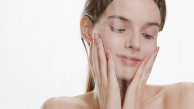 Young woman touches face behind fogged glass on white background